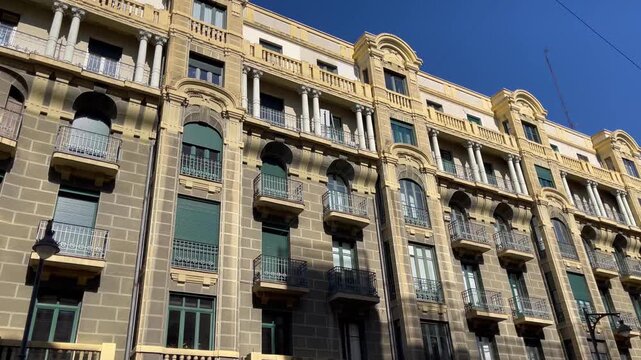 Low-angle view of a historic residential building facade in Valladolid, Spain, featuring classic Spanish architecture with balconies and stone masonry. Real estate, urban lifestyle concepts