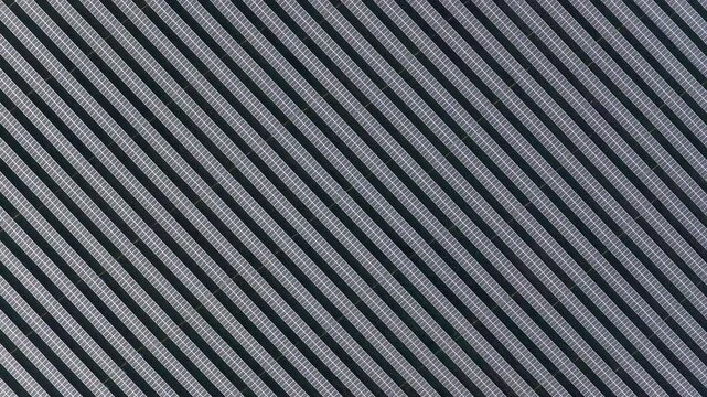 Aerial view of a vast array of solar panels creating a geometric pattern with alternating dark and light diagonal stripes, Wittelsheim, Grand Est, France.