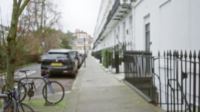 Defocused view of a london street in chelsea, showcasing winter trees and parked cars along a typical united kingdom city sidewalk.