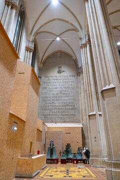 Tall interior wall of Zagreb Cathedral featuring Glagolitic script inscription and historic bells displayed inside the church. Unique cultural and religious heritage detail
