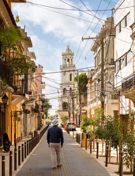 Man in Panama hat walking the street in Zona Colonial of Santo Domingo with Palacio Consistorial in the background