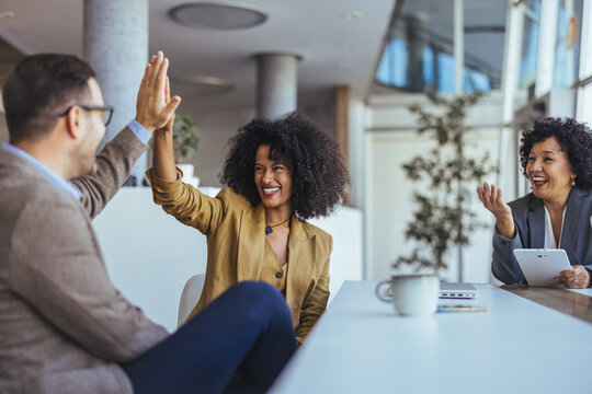 Friends Celebrate Success With A High Five In A Modern Office Meeting Room