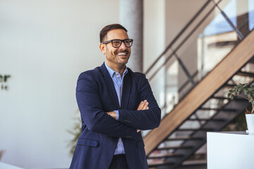 Confident Businessman With Glasses Smiling In Modern Office Lobby And Staircase Background