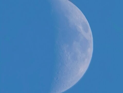 Crescent moon against blue sky with craters, Night sky feature showing moon with shadows and craters