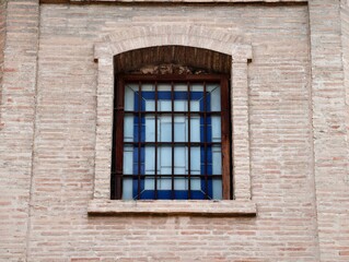 Obraz premium Vintage brick window with iron grille, Aged brick setting with metal grille and textured masonry wall