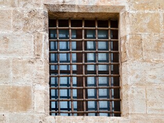 Obraz premium Industrial style window with reflections, Stoneframed window featuring reflective glass and iron bars