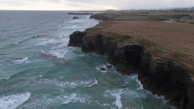 Aerial view of the rugged coastline of Praia das Catedrais where turquoise waters meet the dramatic cliffs, creating a stunning contrast, Praia das Catedrais, Galicia, Spain.