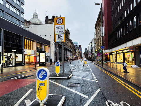 Busy Manchester street with shops, traffic signs and pedestrians in the city centre