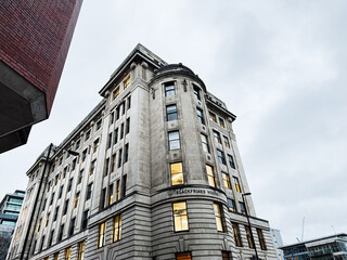 Naklejka premium Historic Manchester building Blackfriars House rises among surrounding streets under a cloudy sky