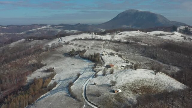 Aerial view of snow blankets the rolling hills and scattered dwellings in Holbav creating a serene winter landscape, Holbav, Brasov, Romania.
