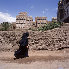A veiled Muslim woman walks on a Sana a street, Yemen.
