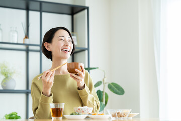 朝食で味噌汁を飲むミドルの女性