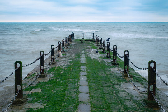 A pair of crows sit on a jetty, winter sea view in Brighton, United Kingdom