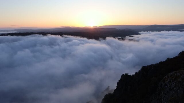 Aerial view of a sea of clouds at sunrise, softly illuminated, contrasting with the dark, rocky cliffs of Canyon du Sil, Sober, Lugo, Spain.