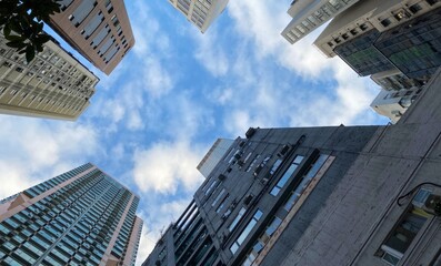 Naklejka premium Urban skyscraper canyons cradle the azure sky, echoing International Sky Day whispers and urban exploration zeal under cloud-kissed frames
