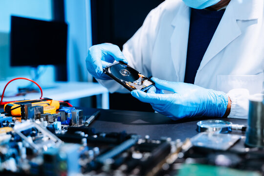 Professional technician repairing hard drive for data recovery in modern technology lab. Digital storage, cybersecurity, hardware repair and data protection concept.