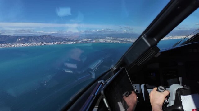Immersive pilot&rsquo;s eye view inside a jet airplane in the final appoach to Malaga airport (AGP), with a view of the pilot hand grasping the yoke, and the coastal runway ahead.