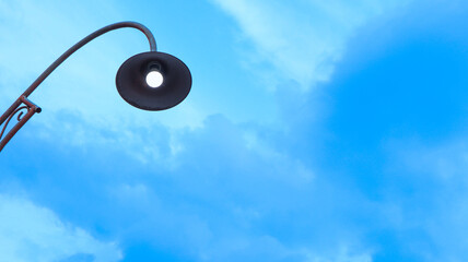 A street lamp stands tall against a vibrant blue sky with scattered clouds on a sunny day IMG 4101 © Belva