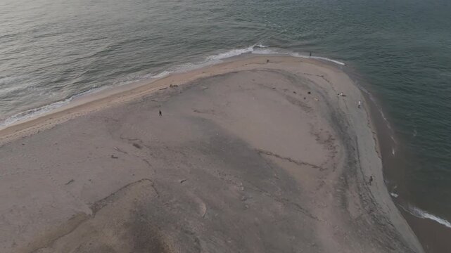 Aerial drone view of Querim Beach, North Goa, revealing a long sandy coastline with scattered rocky outcrops, rows of trees, and the Arabian Sea under soft winter evening light