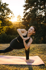 Smiling woman practicing twisted lunge yoga pose outdoors at golden hour, enjoying mindful movement and connection with nature during a yoga session.