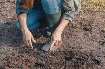 Woman prepares soil for planting, symbolizing connection with nature for commercial and lifestyle stories.