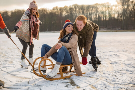Friends having fun with sledge on frozen lake