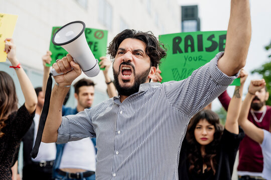 Man holding megaphone screaming with protestors on street