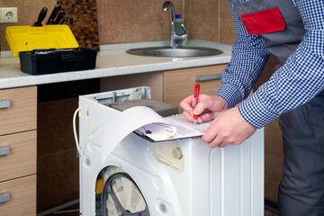 A professional repairman washing machine writing an invoice on home kitchen.