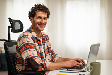 Portrait of young businessman using laptop while enjoying working at his cozy living room.	
