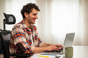 Happy young businessman using laptop while enjoying working at his cozy living room.	