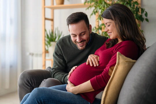 Beautiful pregnant woman and her handsome husband are smiling while spending time together