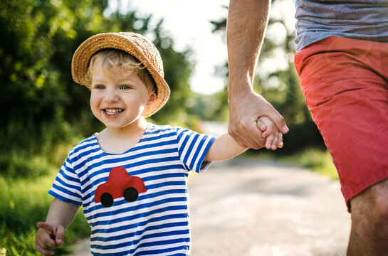 Portrait of laughing toddler walking on father's hand