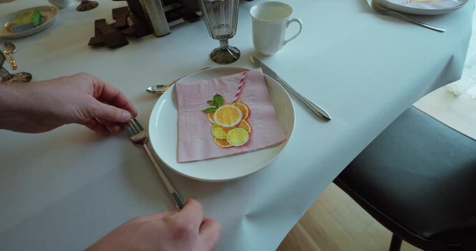 Elegant stock footage showing a hand placing a decorative napkin on a table setting, symbolizing table preparation, hospitality, dining etiquette, and a cozy home meal atmosphere.