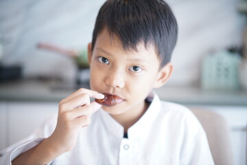 Asian Muslim Boy Breaking Fast with Dates at Home During Ramadan in close up 