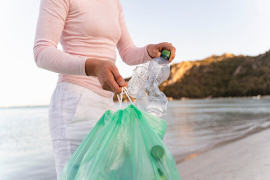 Woman collecting empty plastic bottles on the beach