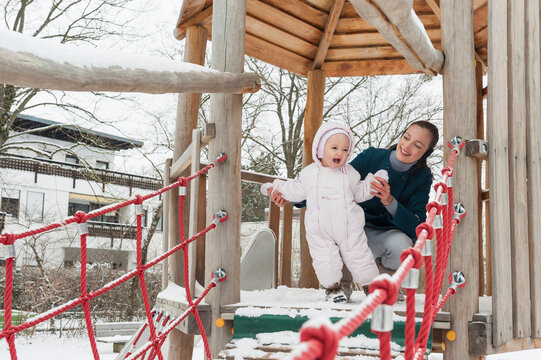 Mother and little daughter on climbing frame in winter