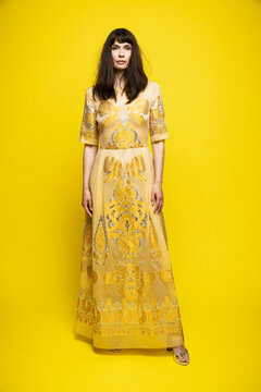 Mature woman wearing dress standing against yellow background