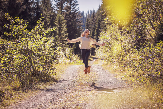 Girl running and jumping on a forest path, having fun
