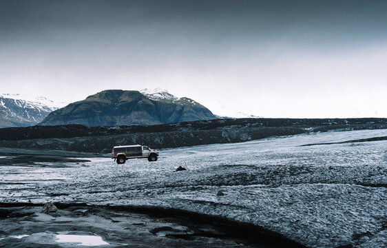 Mini van amidst dramatic landscape in Jokulsarlon, Iceland