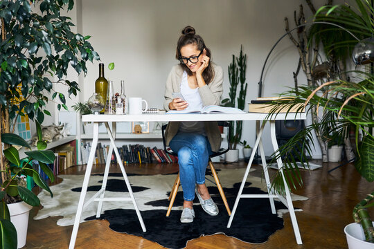 Female student learning at home checking messages on her phone