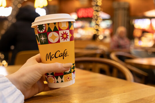 Poznan, Poland - November 19, 2025: McCafe branded disposable coffee cup held by a customer, enjoying a warm refreshing beverage in a welcoming cafe atmosphere