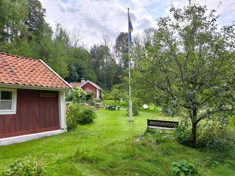 Rasmus Kvarn, Sweden - August 30th 2024: View of Rasmus Kvarn, a traditional wooden water mill with a red tiled roof, wooden footbridge and surrounding forest landscape in Sweden