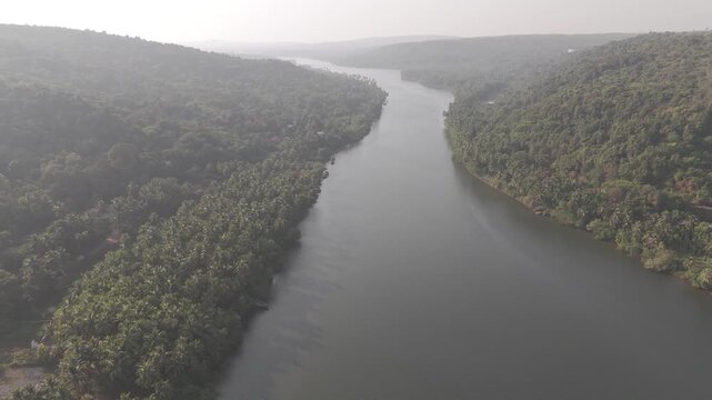 Aerial view of the Tiracol River at the Goa&ndash;Maharashtra border in winter, showing coastal vegetation, mangroves, dry deciduous forest, coconut palms, and native trees along tidal saline waters