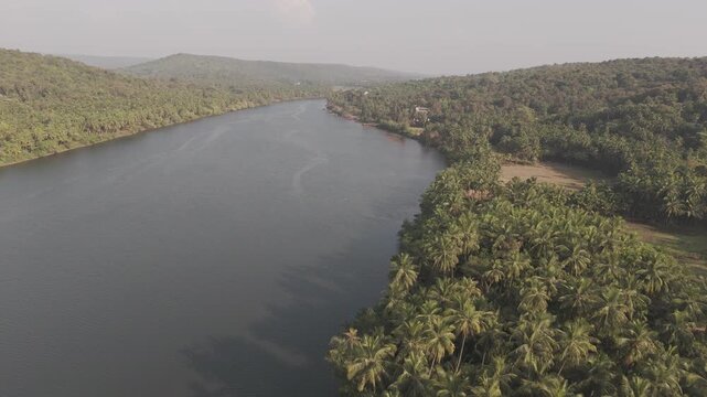Aerial view of the Tiracol River at the Goa&ndash;Maharashtra border in winter, showing coastal vegetation, mangroves, dry deciduous forest, coconut palms, and native trees along tidal saline waters