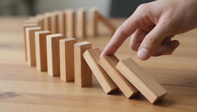 Finger pushing a domino block to start a chain reaction on a wooden table