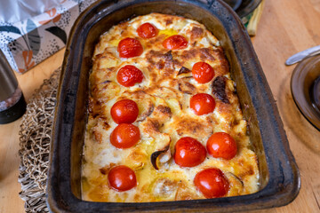 Gratinated creamy potatoes with cheese and potato in big baking dish