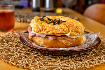 Bagel with ham, cheese and salad leaf on plate, glass of fruity tea.
