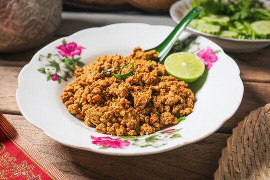 Thai Southern Style Dry Curry with Minced Pork, known as Khua Kling, served in a vintage floral plate with fresh vegetables and lime.