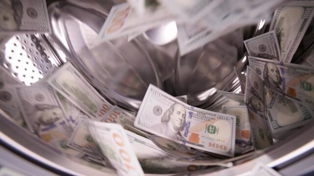 Hundred United States Dollar banknotes inside washing machine for money laundering and fraud concept.