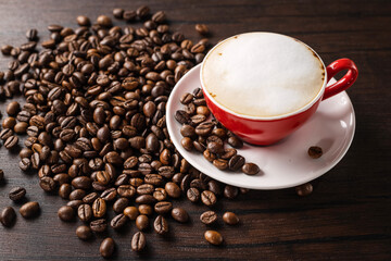 Lots of aromatic coffee beans with coffee in a red cup on a dark background